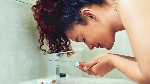 Person sköljer ansiktet över handfatet efter träning
